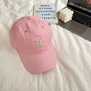 Close-up of pink cotton baseball cap with embroidered R letter in a cozy lifestyle setting