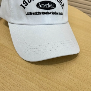 Detailed embroidery on a white cotton baseball cap with multi-row stitching on the brim