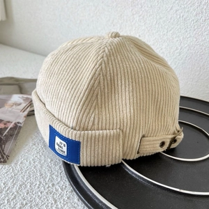 Detail of beige corduroy miki hat showing blue fashion tag and adjustable strap
