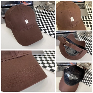 Detailoverzicht van bruine baseballcap met wit geborduurde B en metalen verstelbare gesp