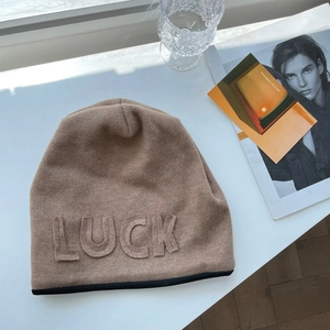Detailed close-up of the Luck letter embroidery on the stylish camel knit beanie hat