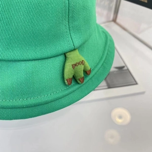 Détail du chapeau bob vert avec griffes de monstre brodées et texte Good brodé