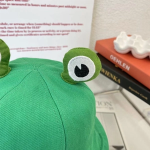 Gros plan du bob grenouille vert avec broderie d'yeux en 3D et détails de texture en toile