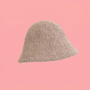 Dettaglio cappello pescatore beige in finta lana d'agnello riccia su sfondo rosa puro