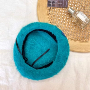 Detailed view of plush teal beret with adjustable inner strap and soft wool texture
