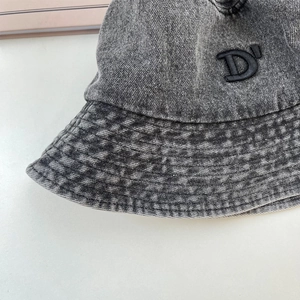 Dettaglio del cappello a secchiello in denim grigio con lettera D ricamata in 3D nera