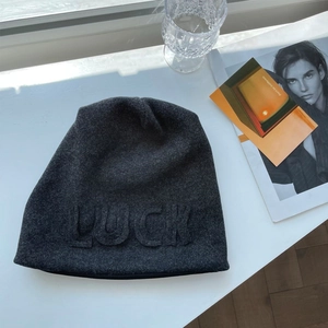 Detail of dark grey knit beanie featuring 3D LUCK lettering and premium wool texture
