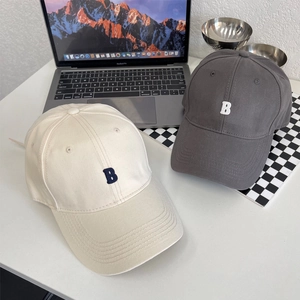 Moderne katoenen honkbalpetten met B-borduurwerk in beige en donkergrijs op een bureau