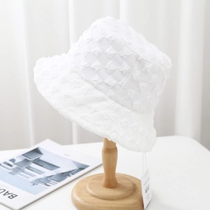 Close-up of white bubble texture bucket hat on wooden stand with detailed fabric view