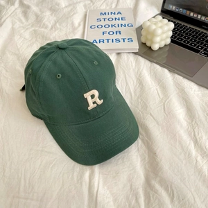 Close-up of R letter embroidery on dark green cotton baseball cap with curved brim