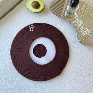 Detail of dark brown knitted beret with embroidered letter P patch and ribbed texture