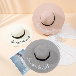 Foldable straw sun hats with black ribbons and 'do not disturb' embroidery in three colors