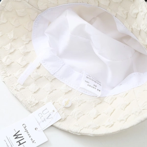Detail view of cream bucket hat interior featuring 100% polyester fabric and UV cut tag