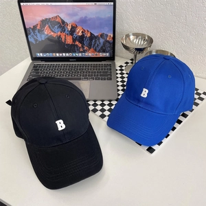 Detailweergave van katoenen baseballcaps met geborduurde letter B op een minimalistisch bureau