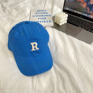 Detailed close-up of blue cotton baseball cap with white 3D letter R embroidery