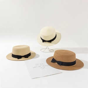 Détail de trois chapeaux de paille canotiers en beige et kaki avec rubans noirs