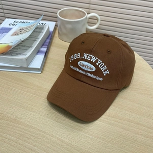 Brown vintage baseball cap with white embroidery on a minimalist wooden table