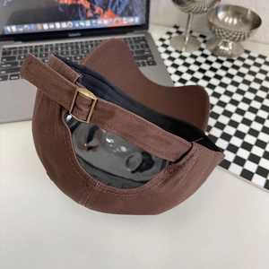 Detail van katoenen baseballpet met verstelbare koperen gesp en riem op witte tafel