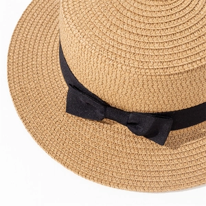 Gros plan détaillé d'un chapeau de paille avec ruban gros-grain noir et petit nœud