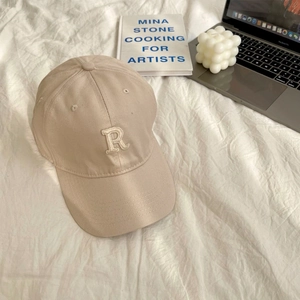 Close-up of beige baseball cap with 3D white embroidered R letter on cotton fabric