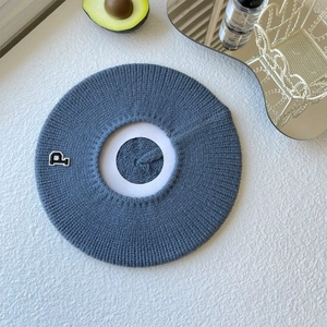 Detail of blue knitted beret showing ribbed texture and letter P patch embroidery