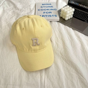Close-up of light yellow baseball cap with R letter embroidery on soft cotton fabric