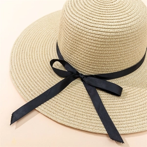 Détail du chapeau en paille beige avec texture tressée serrée et ruban noir élégant