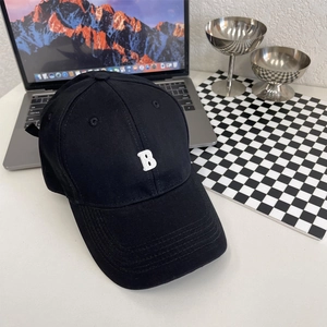 Detail van een zwarte katoenen baseballcap met wit geborduurde letter B op een tafel