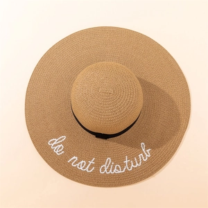 Detail of wide brim straw sun hat with do not disturb embroidery and black ribbon