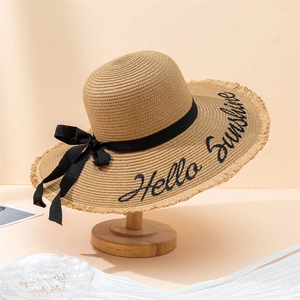 Detail of straw hat featuring Hello Sunshine embroidery and black ribbon bow decoration
