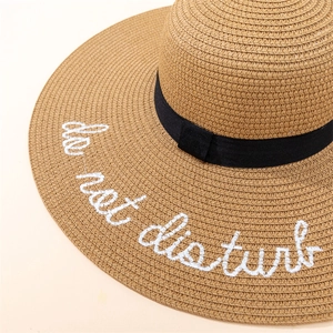 Close-up of straw sun hat brim featuring Do Not Disturb white embroidery detail