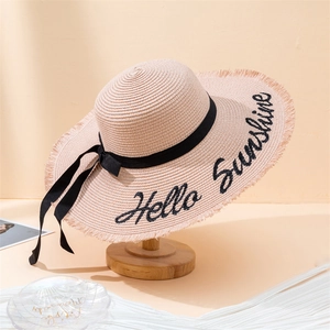 Detail of Hello Sunshine embroidery on a beige straw sun hat with black bow decoration
