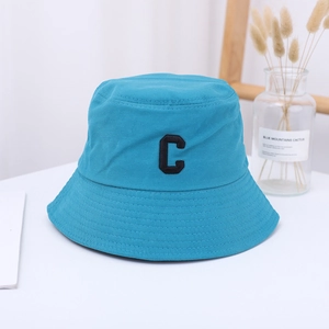 Detail of blue cotton bucket hat with black embroidered C letter and stitched brim