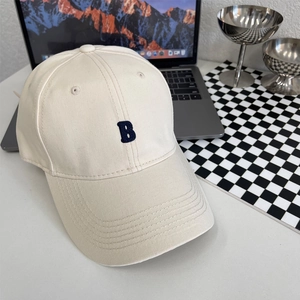 Detailopname van beige katoenen baseballpet met 3D blauw geborduurde letter B erop