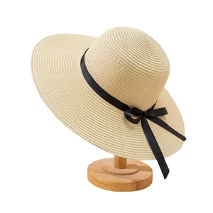 Chapeau de soleil élégant en paille à large bord avec ruban noir sur support en bois