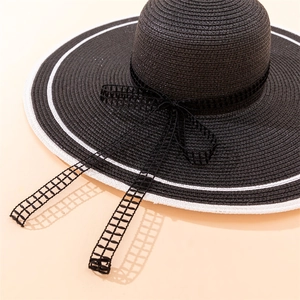 Close-up of black straw sun hat with white brim trim and lace mesh bow detail