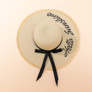 Detail of Hello Sunshine embroidery on a straw sun hat with ribbon and frayed edge