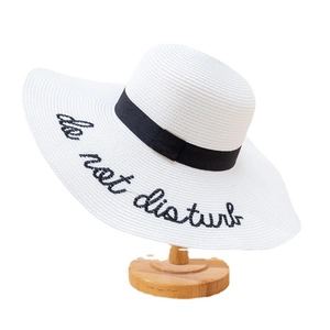 White straw sun hat with black ribbon and Do Not Disturb embroidery on wide brim