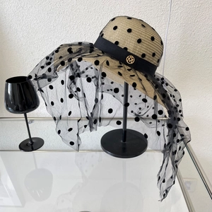 Détail du chapeau de paille élégant avec voile en résille à pois et logo M doré