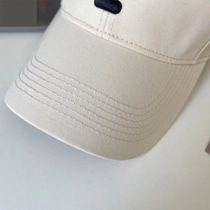 Macro shot of off-white cotton baseball cap showing reinforced stitching and fabric texture