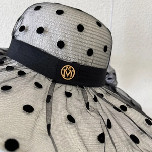 Gros plan d'un chapeau de soleil en tulle à pois noirs avec logo M doré élégant