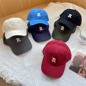 Multiple colors of baseball caps with R embroidery on a stylish fabric background
