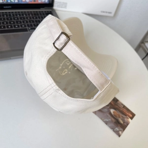 Detail of adjustable metal buckle on beige cotton baseball cap with premium stitching
