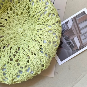 Gros plan d'un béret au crochet vert clair avec des motifs floraux ajourés complexes