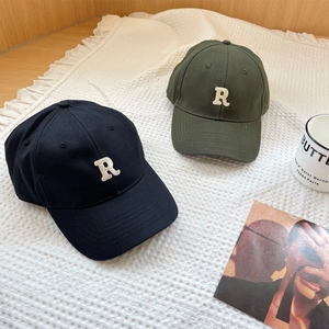 Classic black and olive green baseball caps with R embroidery on a soft textured rug