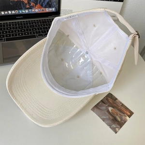 Detail view showing 100% cotton material and inner structure of the beige baseball cap