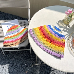 Detailopname van het handgehaakte regenboogstreeppatroon op de strooien vissershoeden