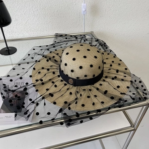 Détail d'un chapeau en paille avec voile en tulle à pois et boucle logo M dorée