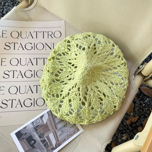 Détail d'un béret au crochet vert clair avec motifs en dentelle et texture tissée fine