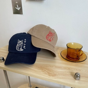 Navy and khaki cotton baseball caps with cat embroidery on a wooden surface